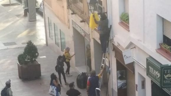 Un grup de persones retira llaços grocs de la via pública