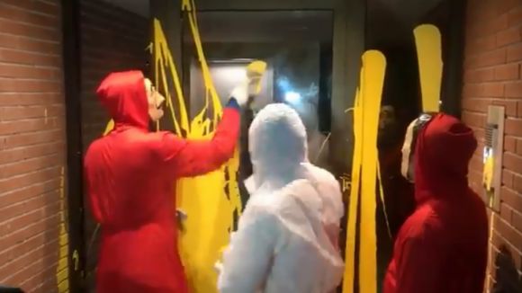 Un grup de persones neteja la pintura groga del portal pintat per Arran