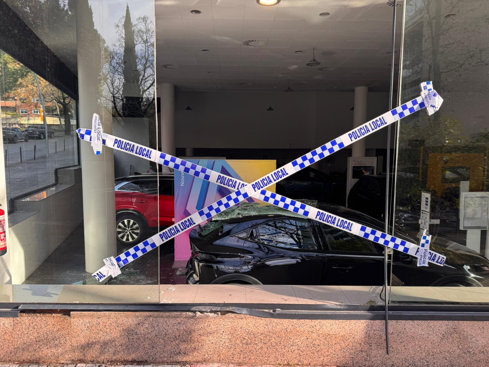 Un cotxe topa amb una jardinera i l'encasta contra el vidre d'un concessionari de Sant Cugat