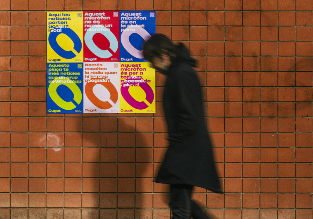 Una persona passeja davant dels cartells promocionals de la nova imatge corporativa de Cugat Mèdia